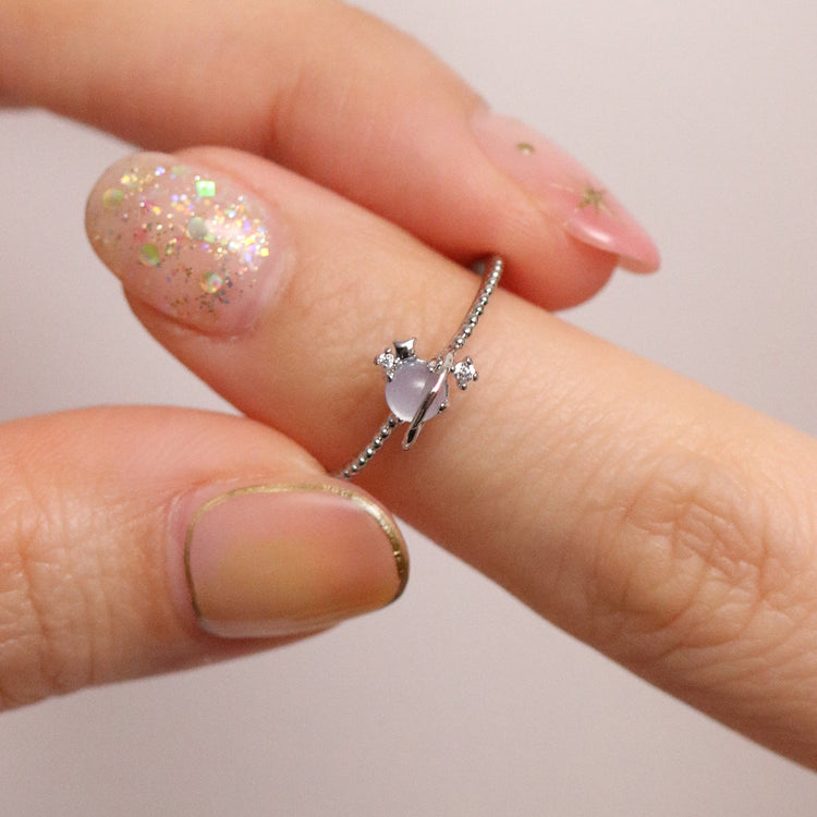 Moonstone Saturn ring on a finger, featuring a delicate design with cosmic motif and sparkling accents.