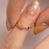 Elegant moon and star ring in gold, worn on a finger with glittery nail polish, perfect for stylish women.